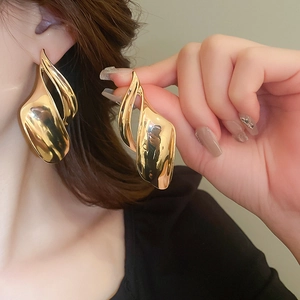 Close-up of golden irregular metal studs earrings with a high-shine polished finish