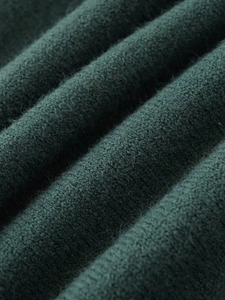 Macro shot of dark green knitted fabric showing fine texture and soft warmth