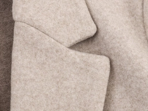 Close-up of oatmeal wool blazer collar showing premium soft fabric and fiber texture