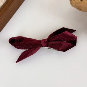 Close-up of burgundy velvet bow hair clip with textured fabric and metal alligator clip