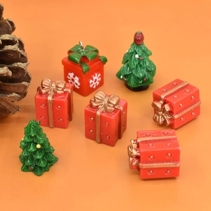 Miniature resin Christmas trees and red gift boxes set on a vibrant orange background
