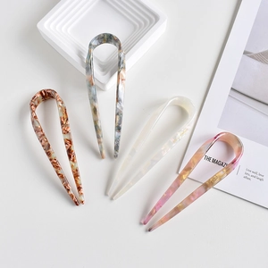 Detailed macro view of four acetate U-shaped hair pins with diverse marble textures
