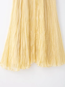Detailed view of the pleated texture and flowing fabric on this light yellow maxi skirt
