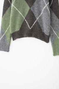 Détails du motif à losanges et ourlet côtelé sur un pull col en V gris et vert décontracté