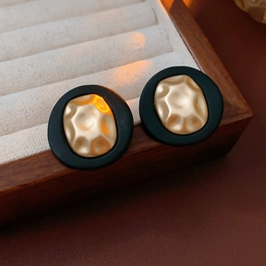 Detail of vintage round stud earrings with black frame and textured gold inlay in a box