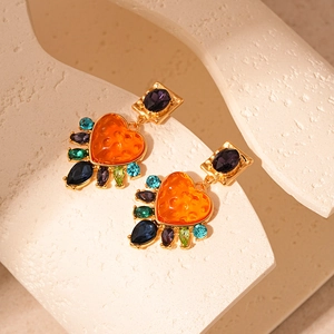 Vintage gold heart earrings with orange resin and colorful gemstones on white stone