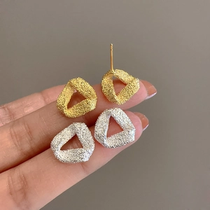 Size comparison of matte triangle earrings in gold and silver finish held by hand