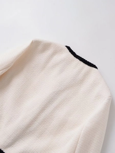 Détail d'une veste en tweed français avec texture beige et bordures tissées noires