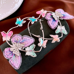 Detail showing embroidered butterfly hoop earrings with sparkling rhinestones and pearls