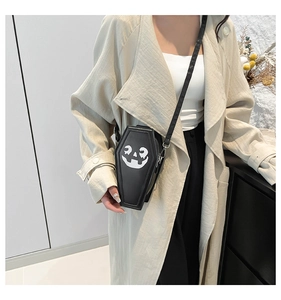 Ghost coffin crossbody bag with pumpkin face print worn by a model in a beige coat
