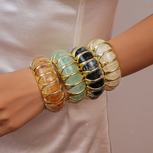 Detailed close-up of stacked acrylic resin bangles in amber, mint, black, and cream white
