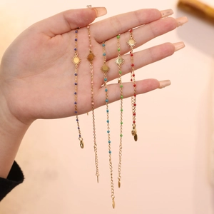 Detail of five colorful sun charm bracelets with gold beads and starburst pendants