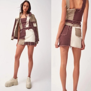 Detail of high-waist patchwork denim skirt set featuring raw hem and back cut-out design