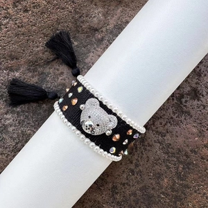 Handmade woven bear bracelet decorated with rhinestones, pearls, and chic black tassels.