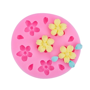 Pink silicone cherry blossom mold with yellow flower and blue leaf fondant decorations