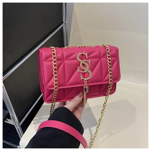 Detail of rose red quilted crossbody bag featuring a gold S-shaped clasp and chain strap