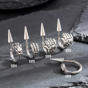 Punk style stainless steel spike earrings with gothic dragon and claw designs on rock