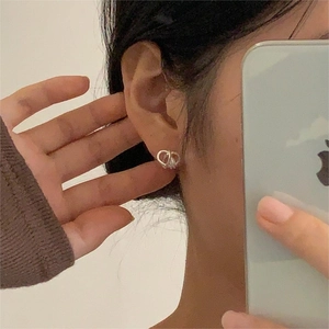 Close-up of silver knot heart earrings worn on ear showing minimalist aesthetic