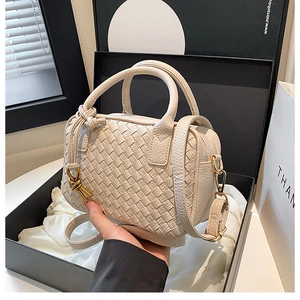 Detailed view of woven beige Boston bag with intrecciato texture in a gift box