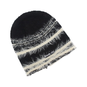Close-up of black and white striped knit beanie with plush faux fur texture and brand tag