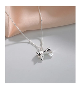 Close-up of polished S925 silver bow pendant necklace with delicate beaded chain detail