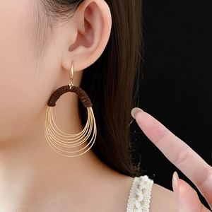 Detail of layered gold oval hoop earrings with brown flocking texture on ear hooks