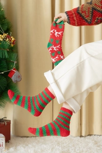 Nahaufnahme flauschiger Weihnachts-Korallenvlies-Socken mit Elchmuster und Streifen