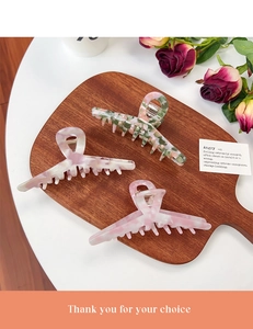 Detailed set of three large marble acetate hair claws on a rustic wooden tray decoration
