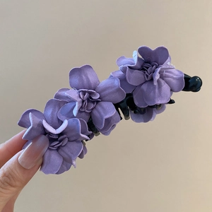 Vue détaillée d'une pince à cheveux à fleurs en tissu violet avec pétales élégants