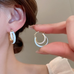 Detail of tulip hoop earrings with white and blue enamel finish on gold circles