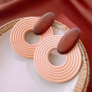 Close-up of bohemian wood drop earrings in pink and brown on elegant ceramic tray