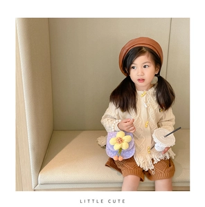 Toddler girl modeling purple floral bag with cream cardigan and brown knit shorts