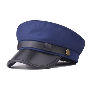 Detail of navy blue flat top beret with black leather brim and vintage gold buttons
