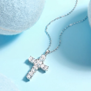 Macro view of sparkling crystal encrusted silver cross pendant on a soft blue base