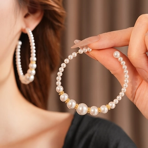 Vista detallada de pendientes de aro en C con perlas y elegantes cuentas doradas