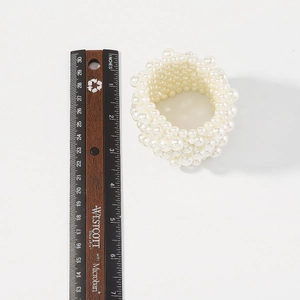 Detail of multi-row elastic pearl beaded wide bracelet with wooden ruler for sizing