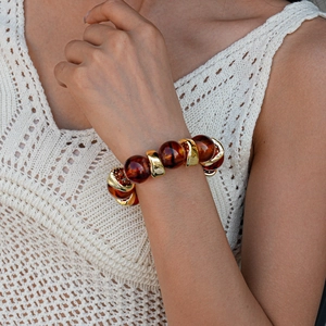 Detailed close-up of retro acrylic amber beads with polished golden metal link bracelet