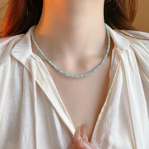 Close-up of minimalist turquoise beaded choker necklace on model with golden lighting