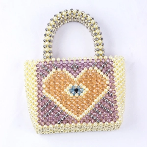 Detailed view of handmade beaded tote bag featuring multi-color pearls and evil eye charm