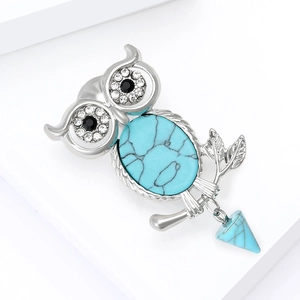 Detail of silver owl brooch featuring turquoise stone wings and sparkling rhinestone eyes