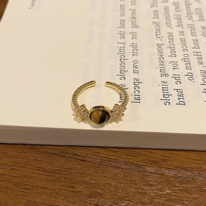 Close-up of 18k gold plated tiger eye ring on a minimalist white book background