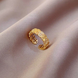 Macro shot of gold-plated adjustable ring with coin pattern and inlaid zircons on silk