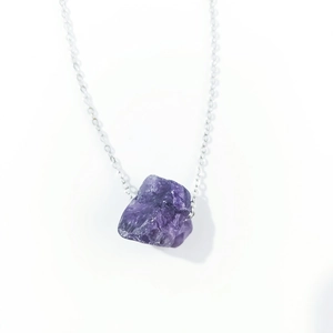 Detailed macro view of raw purple amethyst crystal pendant on silver link chain