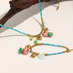Détail de l'ensemble collier et bracelet tressés avec pendentifs poissons sur bois