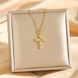 Élégant collier croix dorée avec zircons sur un coffret cadeau en satin champagne
