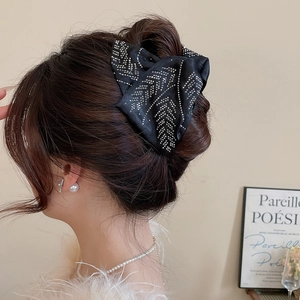 Macro view of black silk bow hair claw featuring elegant silver rhinestone leaf patterns