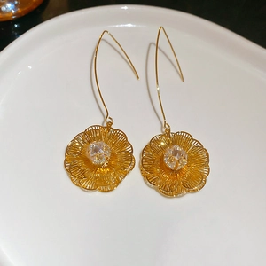 Détail macro des boucles d'oreilles fleurs plaquées or 18 carats avec zircons