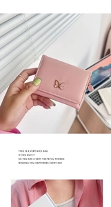 Pink mini wallet with gold butterfly clasp and litchi texture finish in a home setting