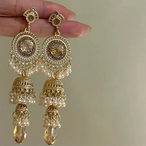 Detailed close-up of golden vintage Jhumka earrings with champagne gems and white pearls