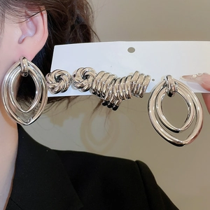Detail of chunky silver layered hoop earrings showing oversized knot design and metallic finish